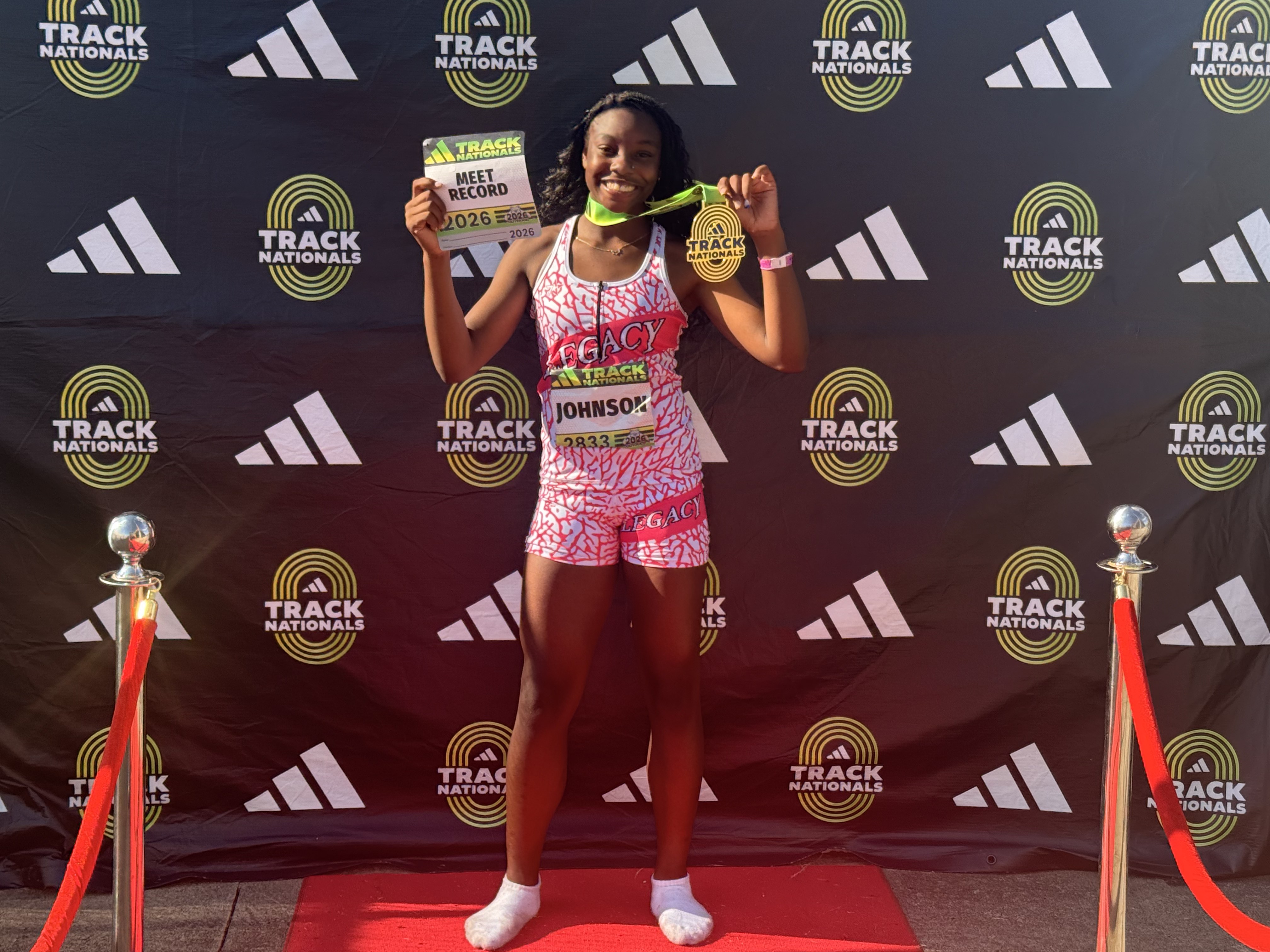 Zoei Johnson holding an adidas Track Nationals Meet Record card and gold medal